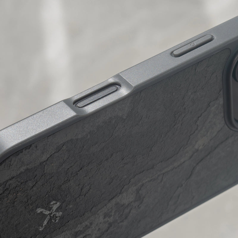 Nahaufnahme des grauen Bumper Cases mit matter Schieferstein-Rückseite, Logogravur und passgenauer Aussparung für die Camera-Control-Taste des iPhone 16.