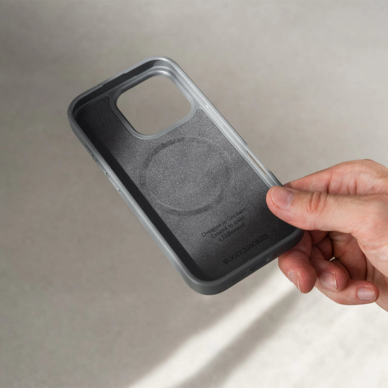 La photo montre l'intérieur rembourré de l'étui noir « iPhone 16 Pro Bumper Case » en noyer, doté d'un anneau MagSafe intégré et du logo Woodcessories en relief.