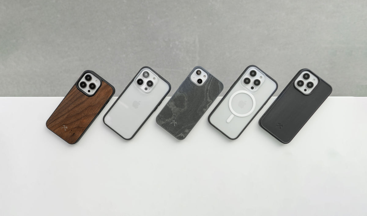 Plusieurs iPhone 14 et iPhone 14 Pro sont posés sur le bord d'une table, protégés par des coques Woodcessories Bio, Clear et Bumper en pierre et en bois.